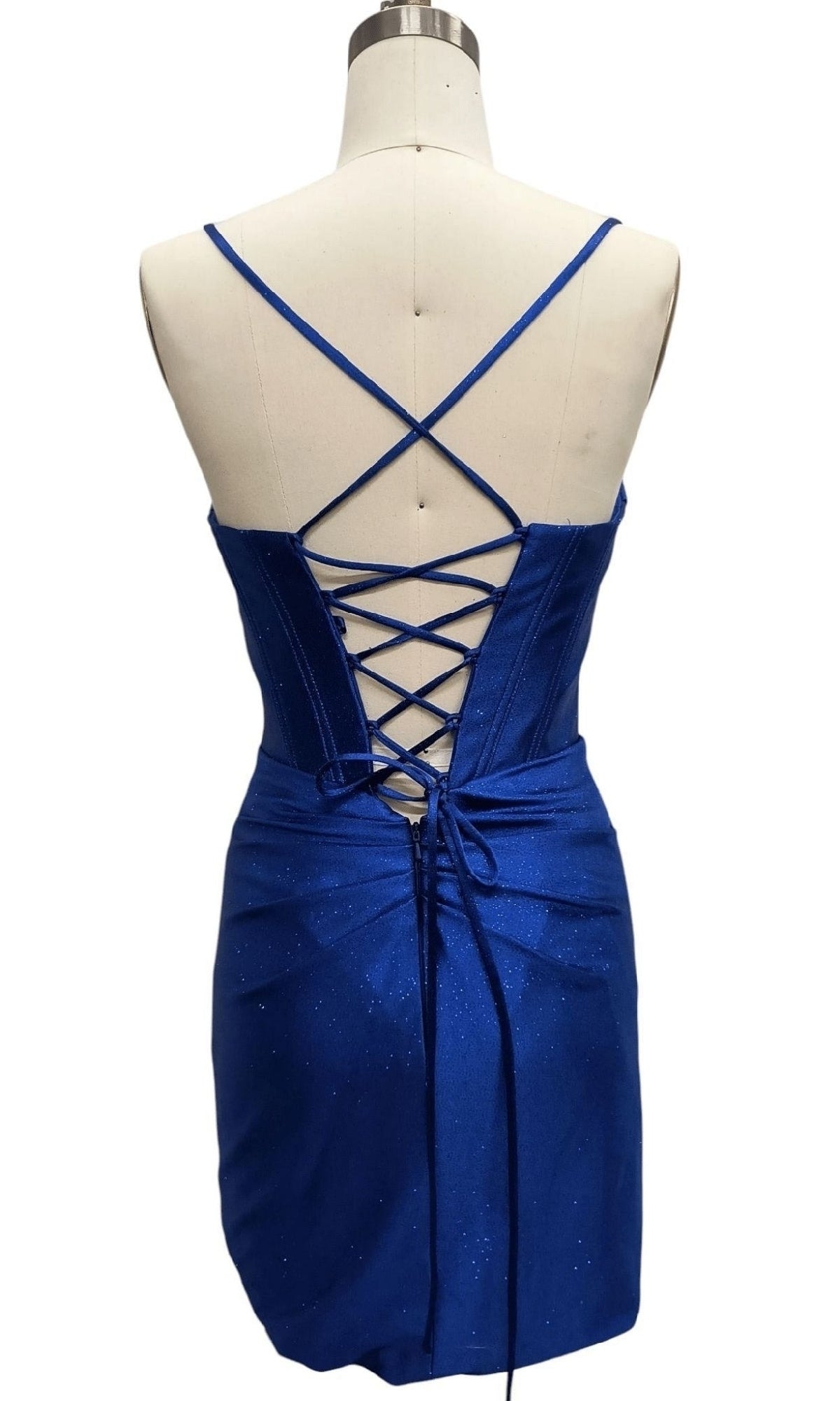 A mannequin displays the Cowl-Neck Blue Hoco Dress: 12618, a short royal blue homecoming dress with thin straps, a cowl neckline, crisscross lace-up back, and a fitted mini skirt.